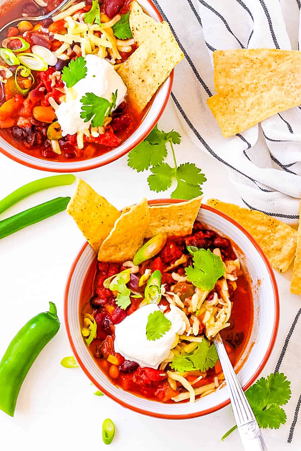 Easy Instant Pot vegetarian chili, served in a bowl garnished with green onions, cheese, sour cream and tortilla chips.