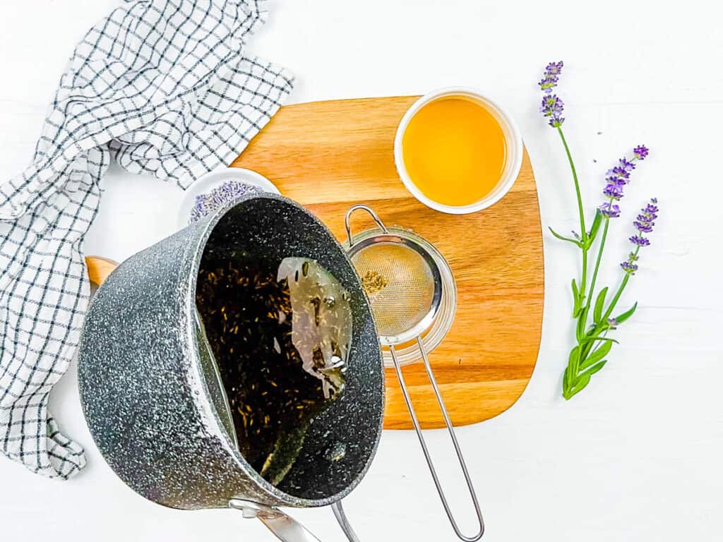 Simple syrup being strained through a mesh strainer.