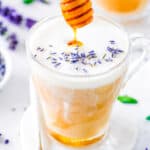 Homemade honey lavender latte served in a glass, garnished with lavender flowers.