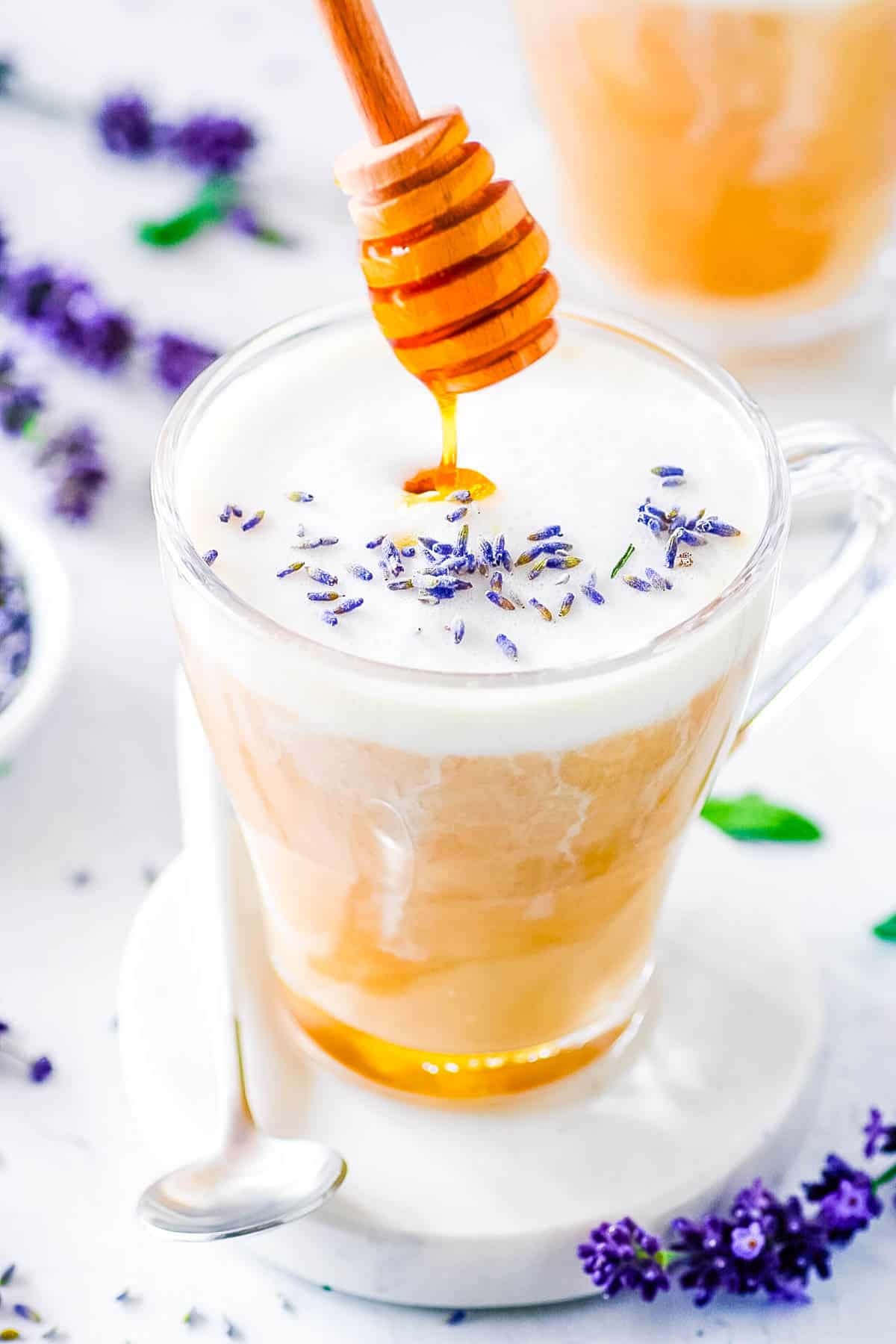 Homemade honey lavender latte served in a glass, garnished with lavender flowers.