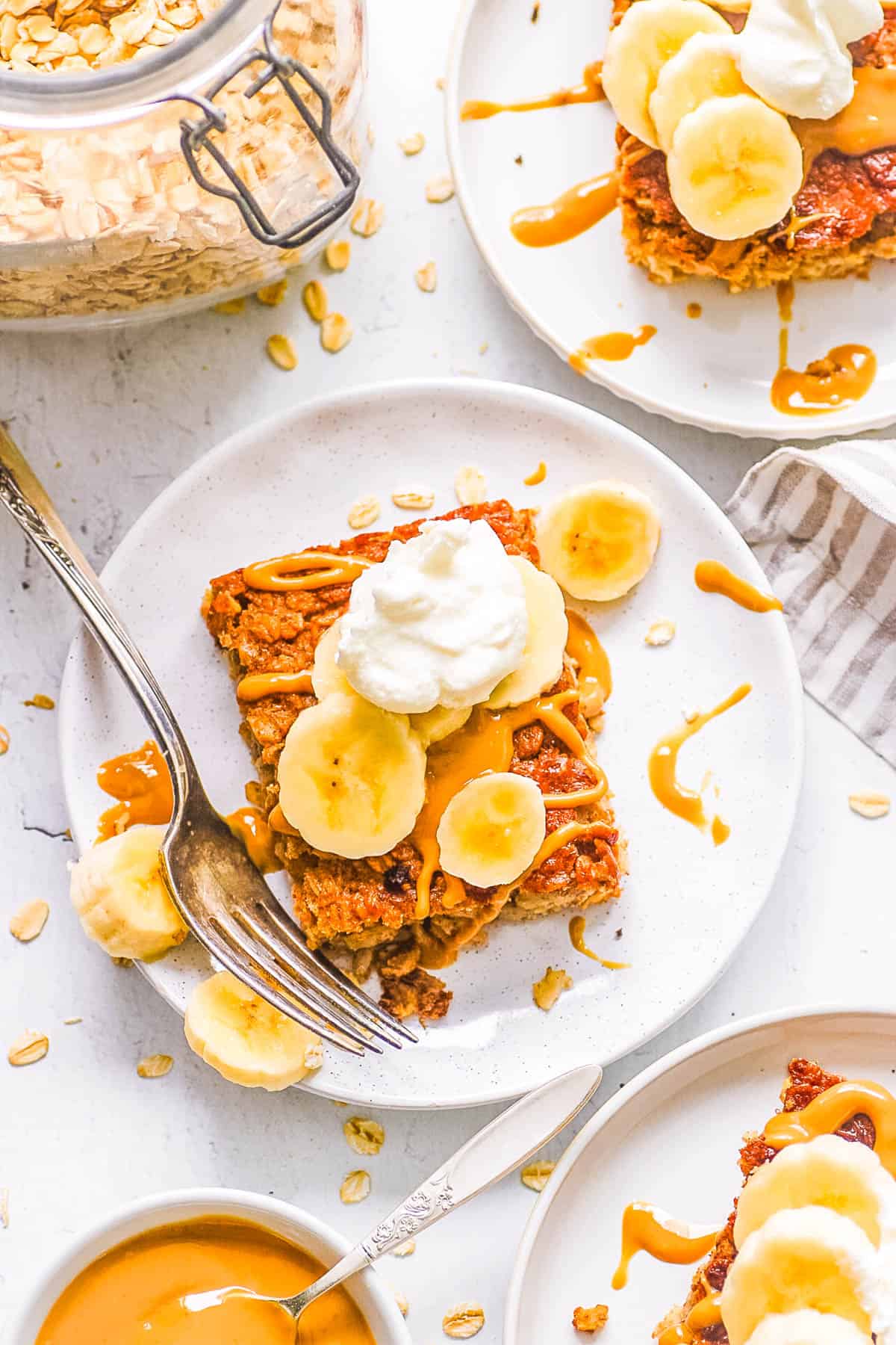 One slice of peanut butter baked oatmeal, garnished with banana slices, served on a white plate with a fork.