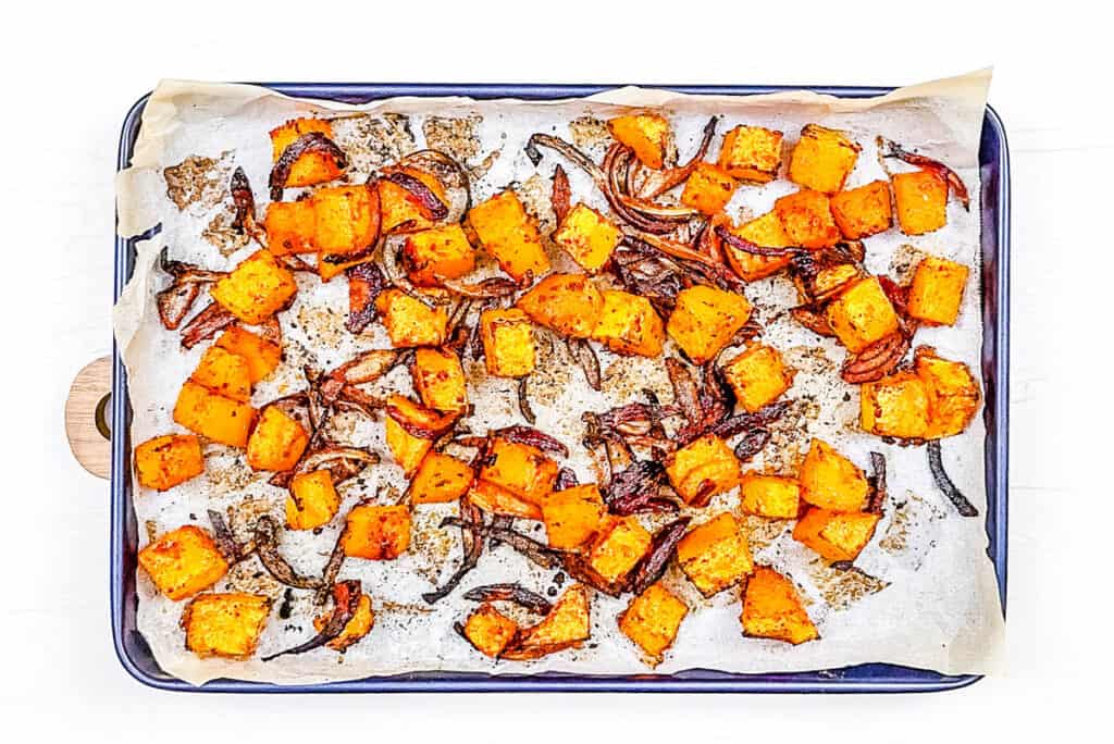 Roasted pumpkin and onions on a baking sheet.