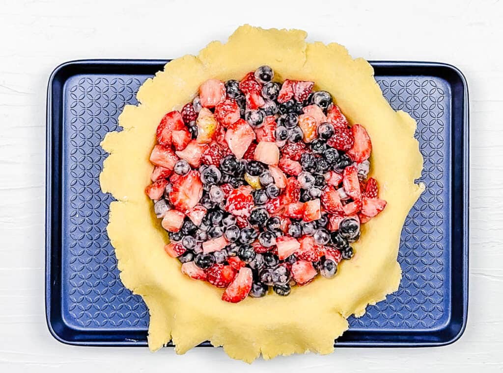 Berry filling added to pie crust in a baking dish.