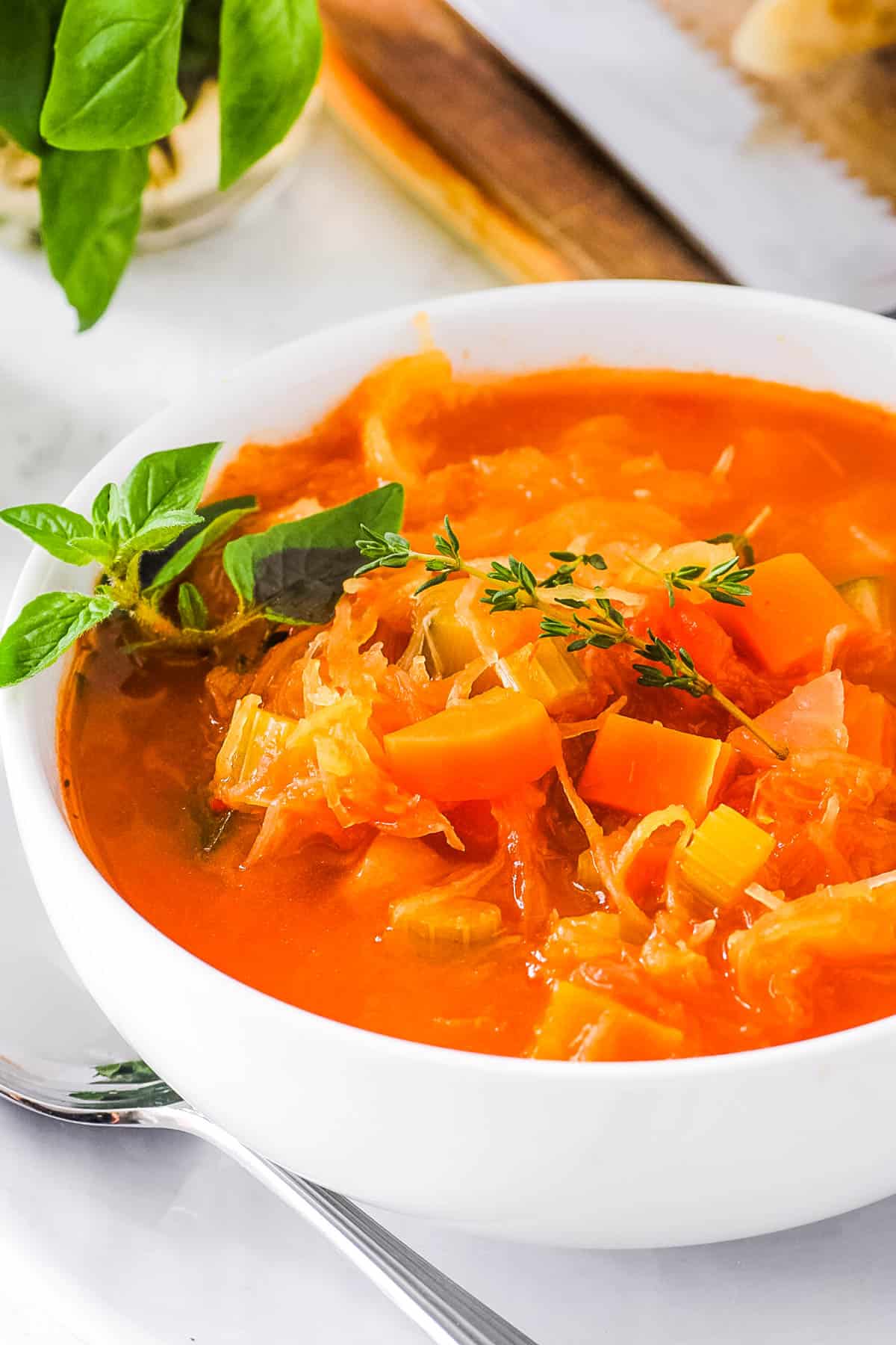 Spaghetti squash soup, served in a white bowl, garnished with fresh herbs.