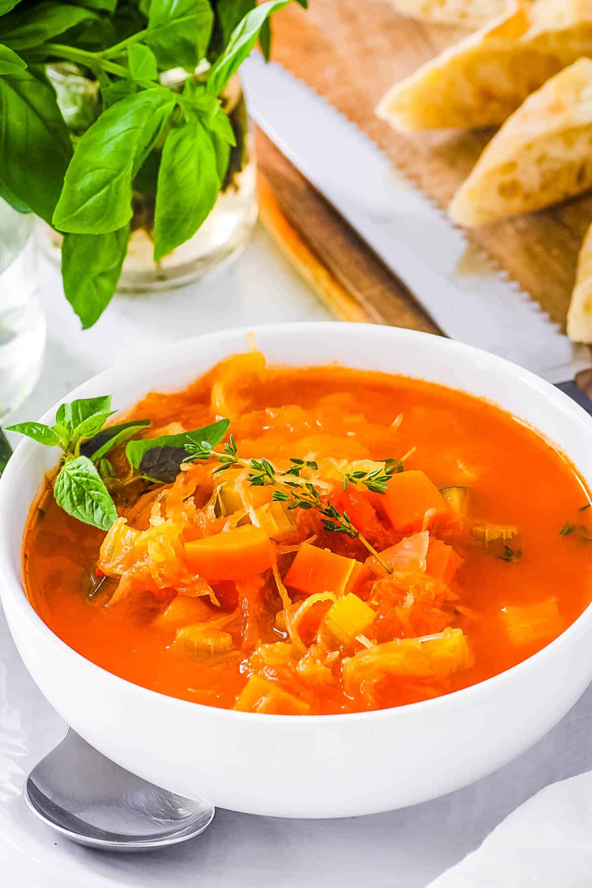 Vegan spaghetti squash soup, served in a white bowl, garnished with fresh herbs.