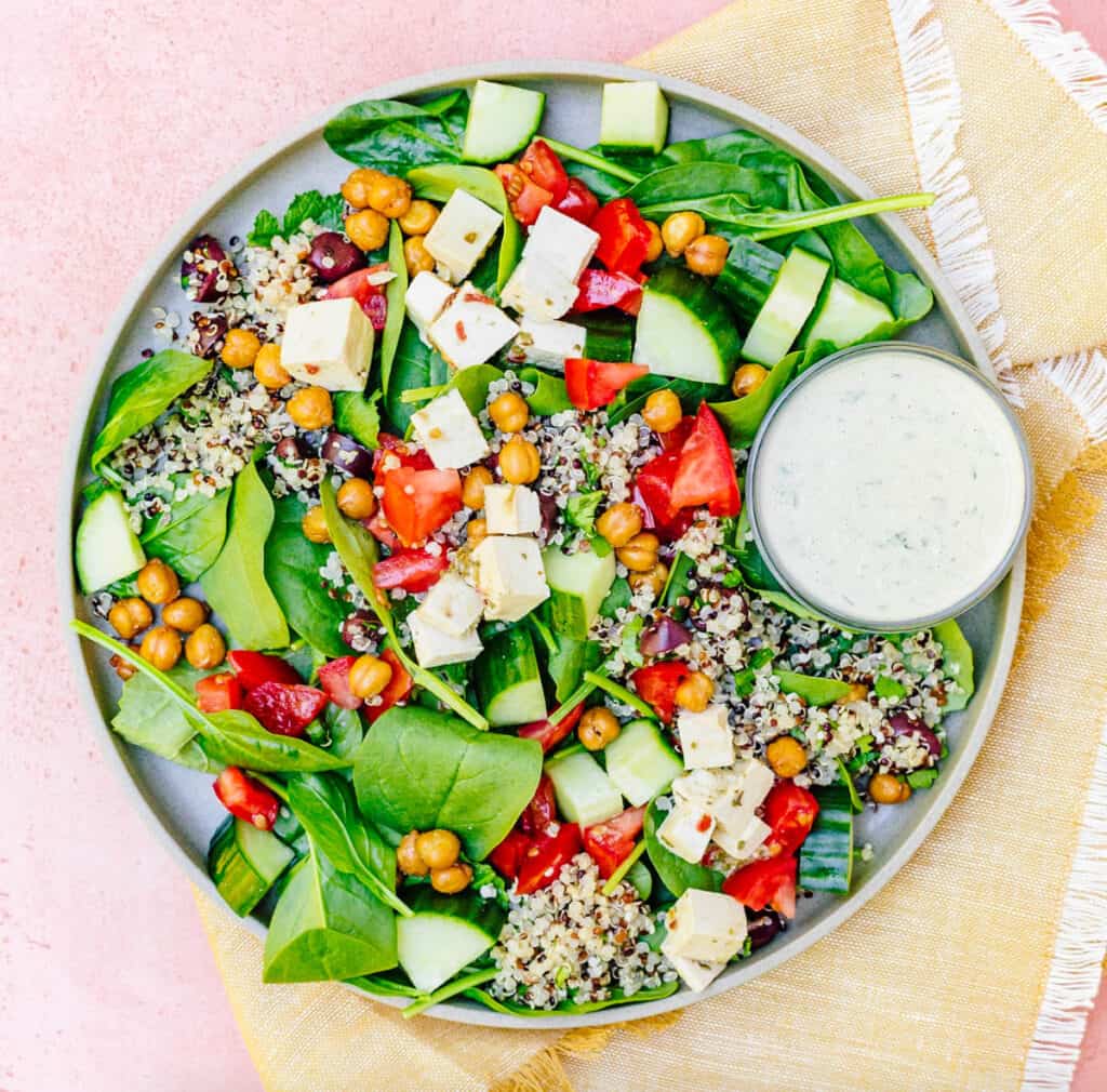 Thistle Greek salad served on a grey plate with a pink background.