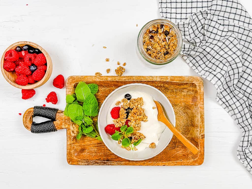 Creamy cottage cheese topped with berries, granola and fresh mint in a bowl.