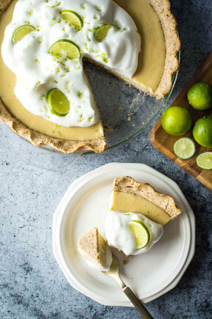 Vegan key lime pie with one slice cut out on a white plate.