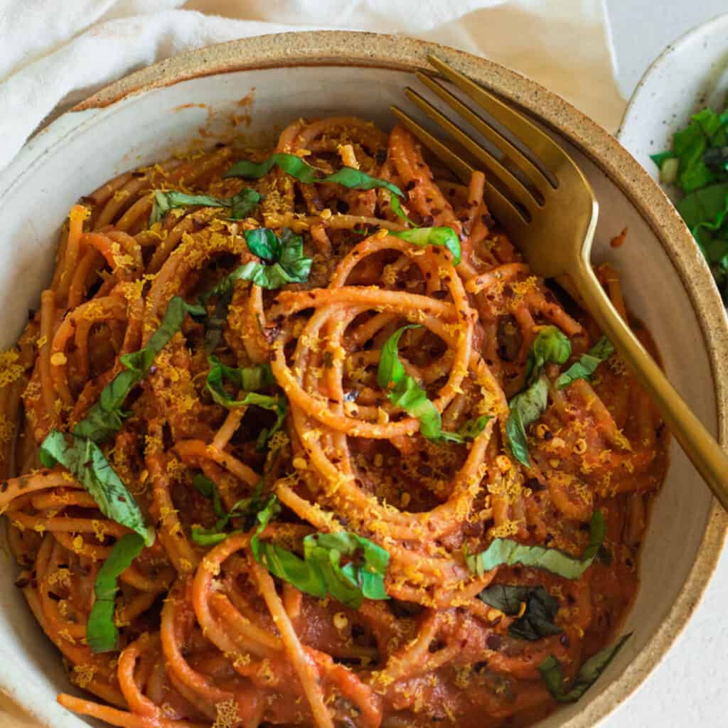 Silken tofu pasta sauce tossed with pasta in a serving bowl.