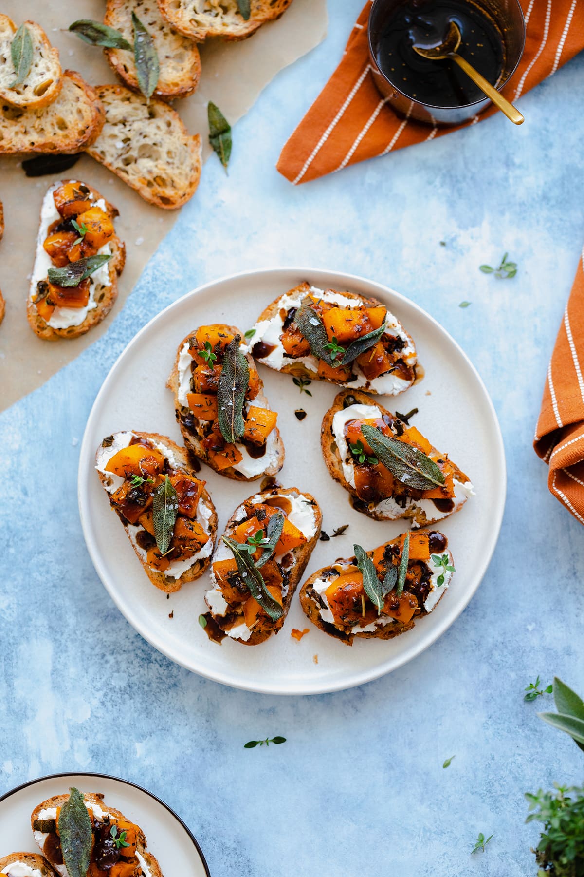 Butternut squash crostini with goat cheese and sage served on a white plate.