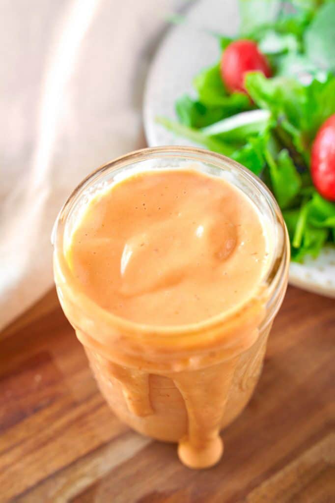 Thousand Island dressing in a glass jar with some dripping down the side.