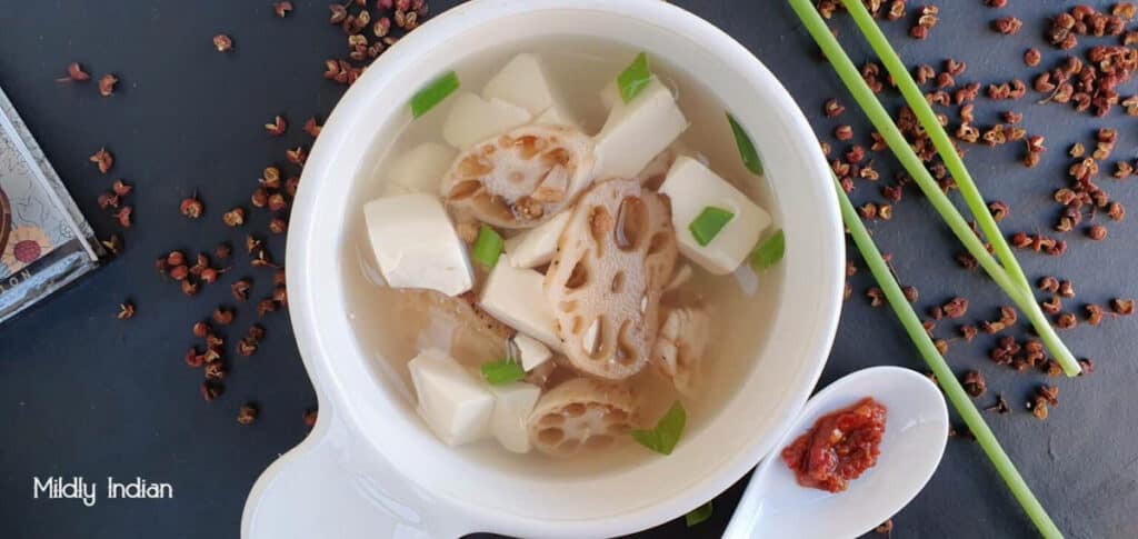 Tofu lotus root soup in a clear broth, in a white bowl.