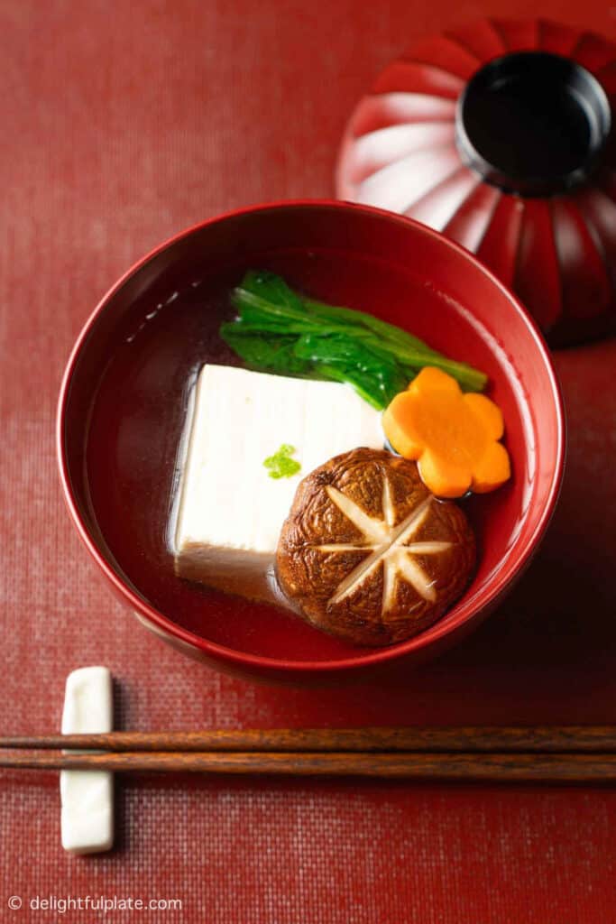 Japanese soup with silken tofu in a red bowl.