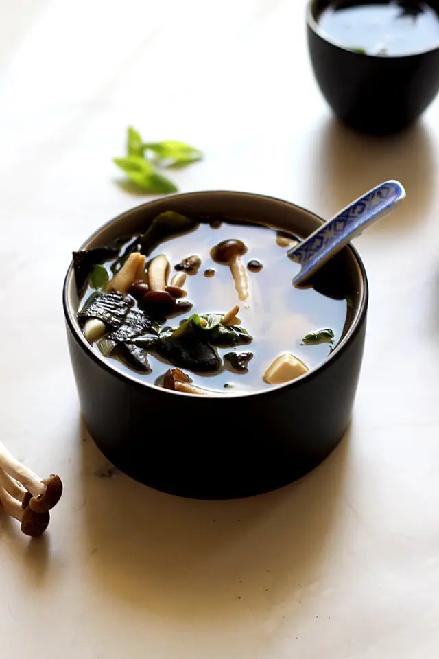 Miso soup in a black bowl.