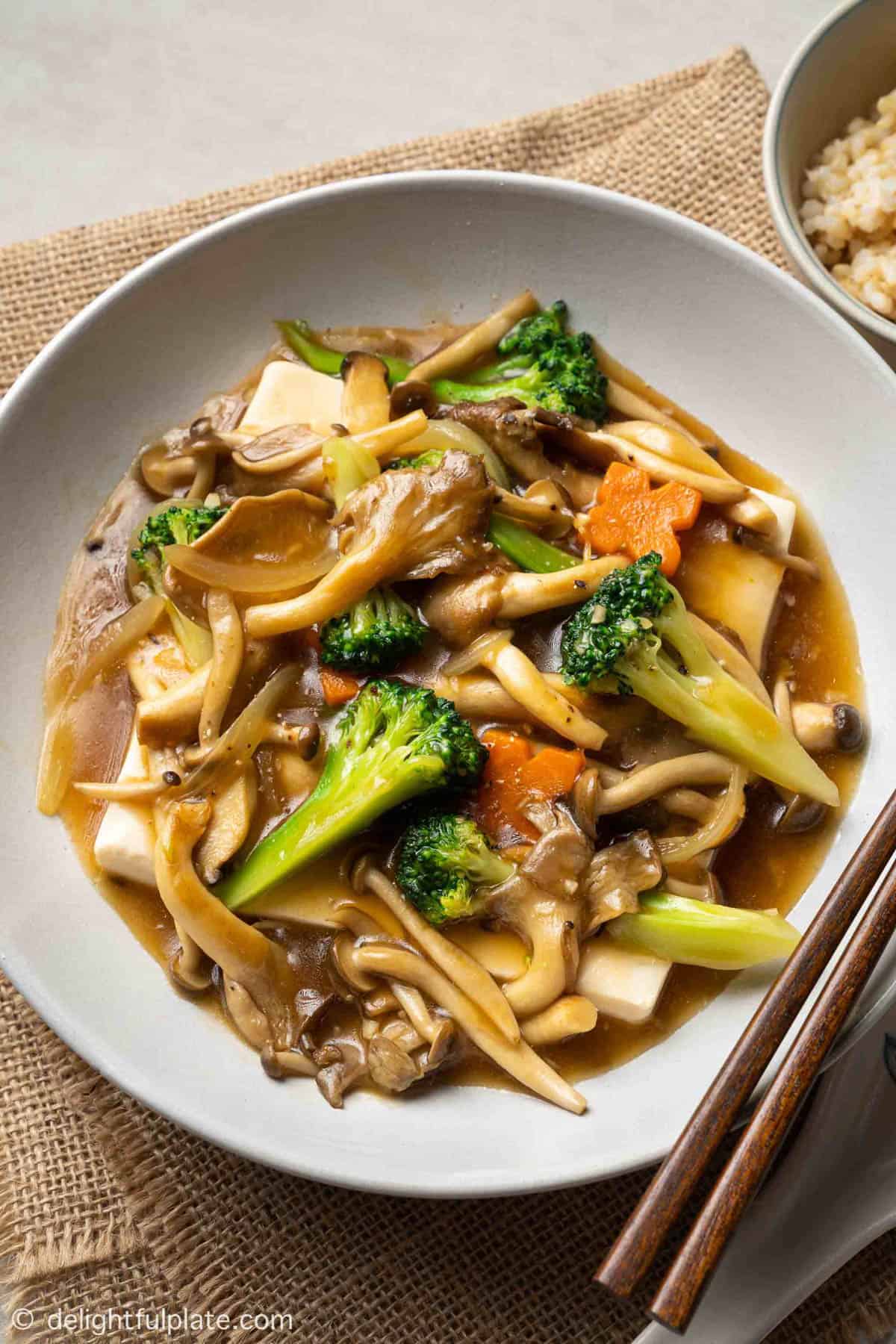 Steamed tofu with mushrooms and veggies in a white bowl.