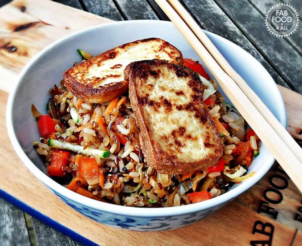 Warm rice and quinoa salad in a white bowl with tofu.