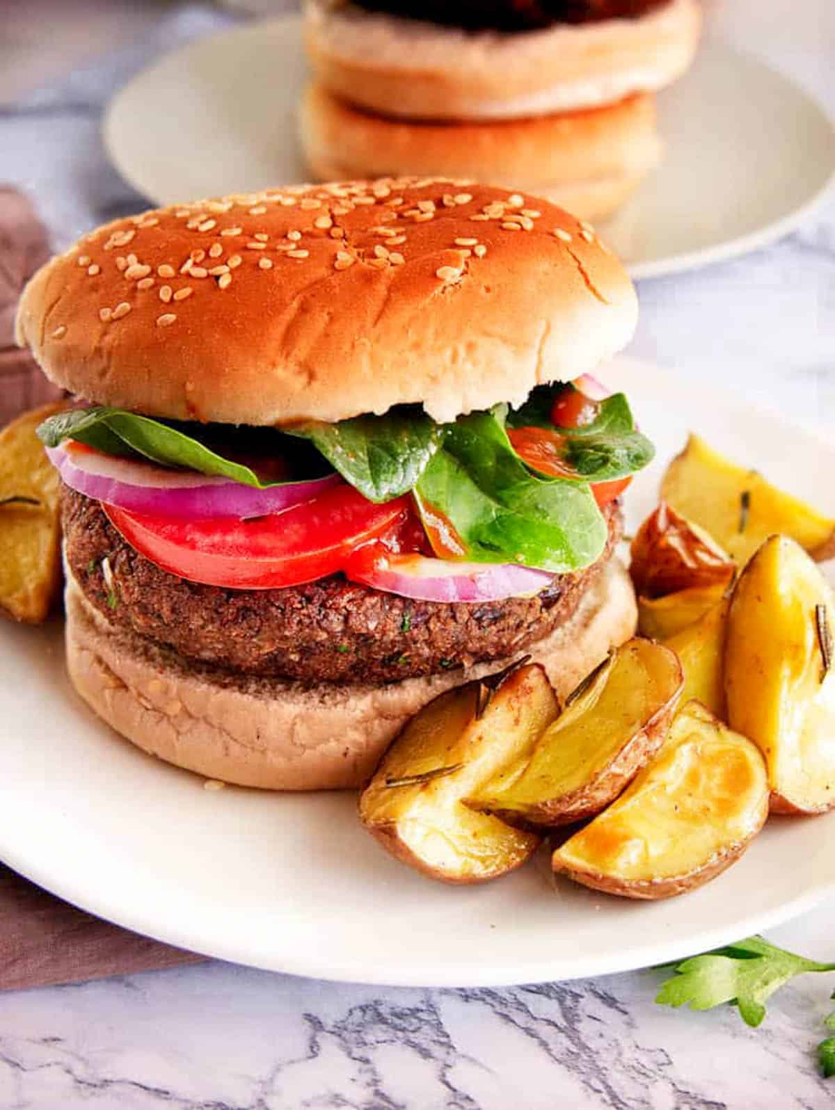 Black bean quinoa burgers on a white plate served with roasted potatoes on the side.