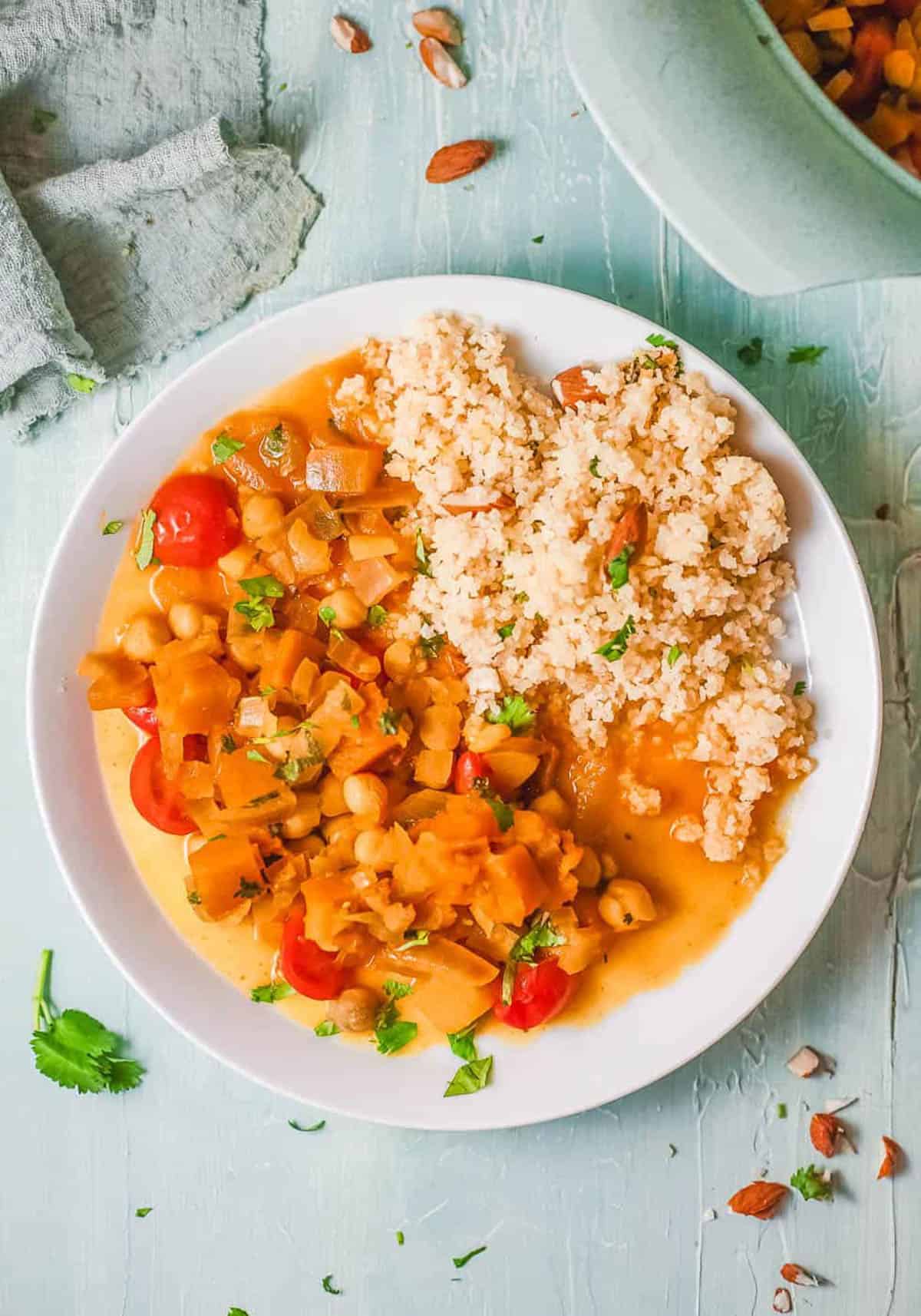 Butternut squash and chickpea curry, served with couscous on a white plate.