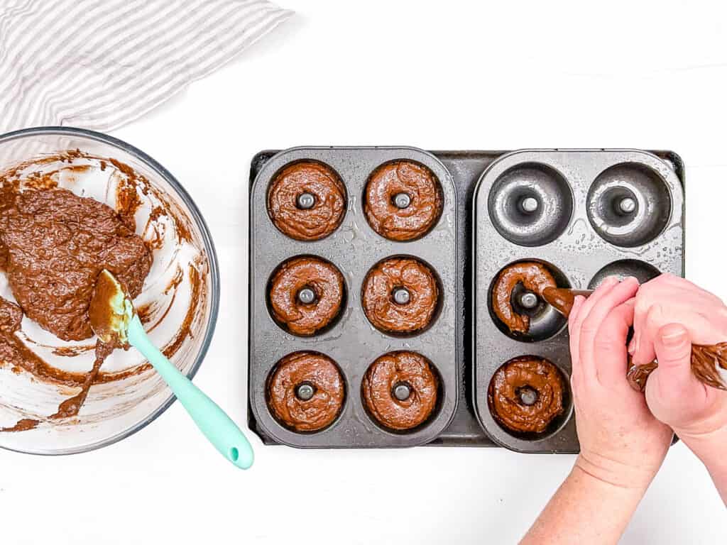 Donut batter being piped into a donut pan.