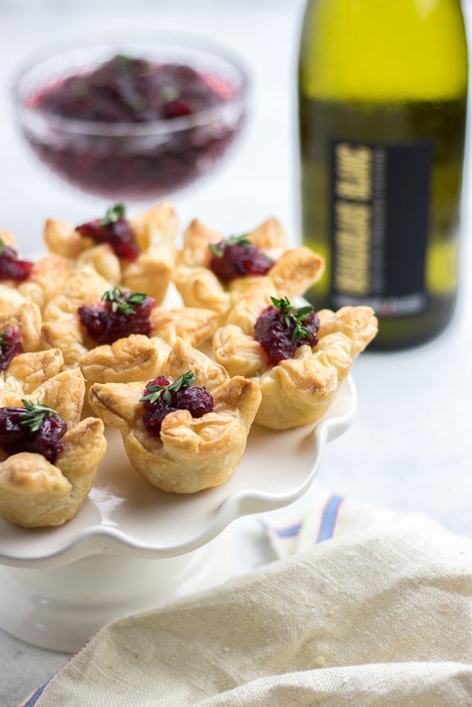 Mini cranberry bites in pastry puff on a white platter.