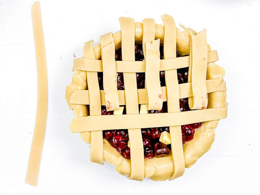 Pie crust being formed into a lattice design on top of a pie.