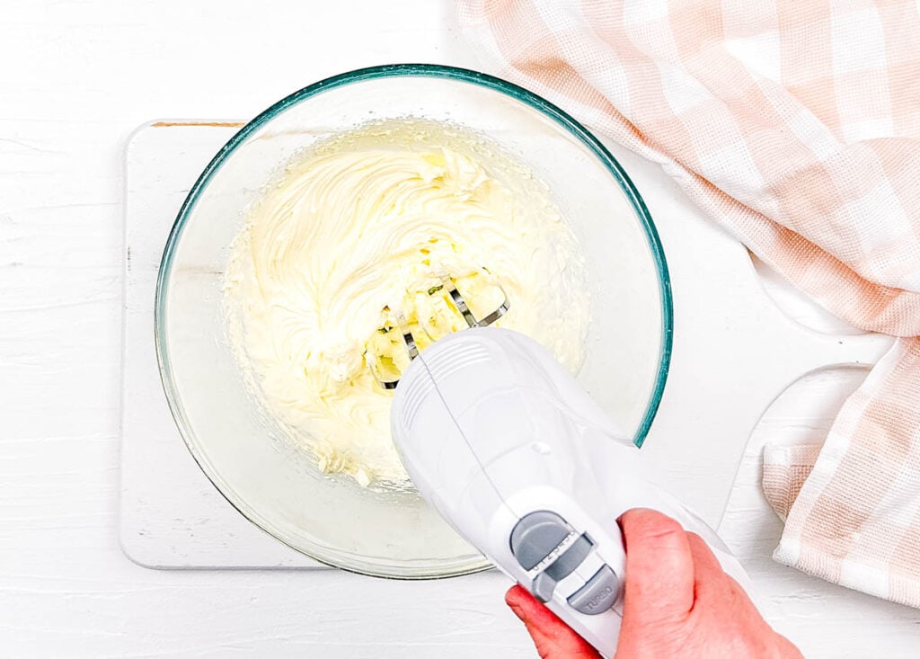 Whipped cream being whipped in a mixing bowl.