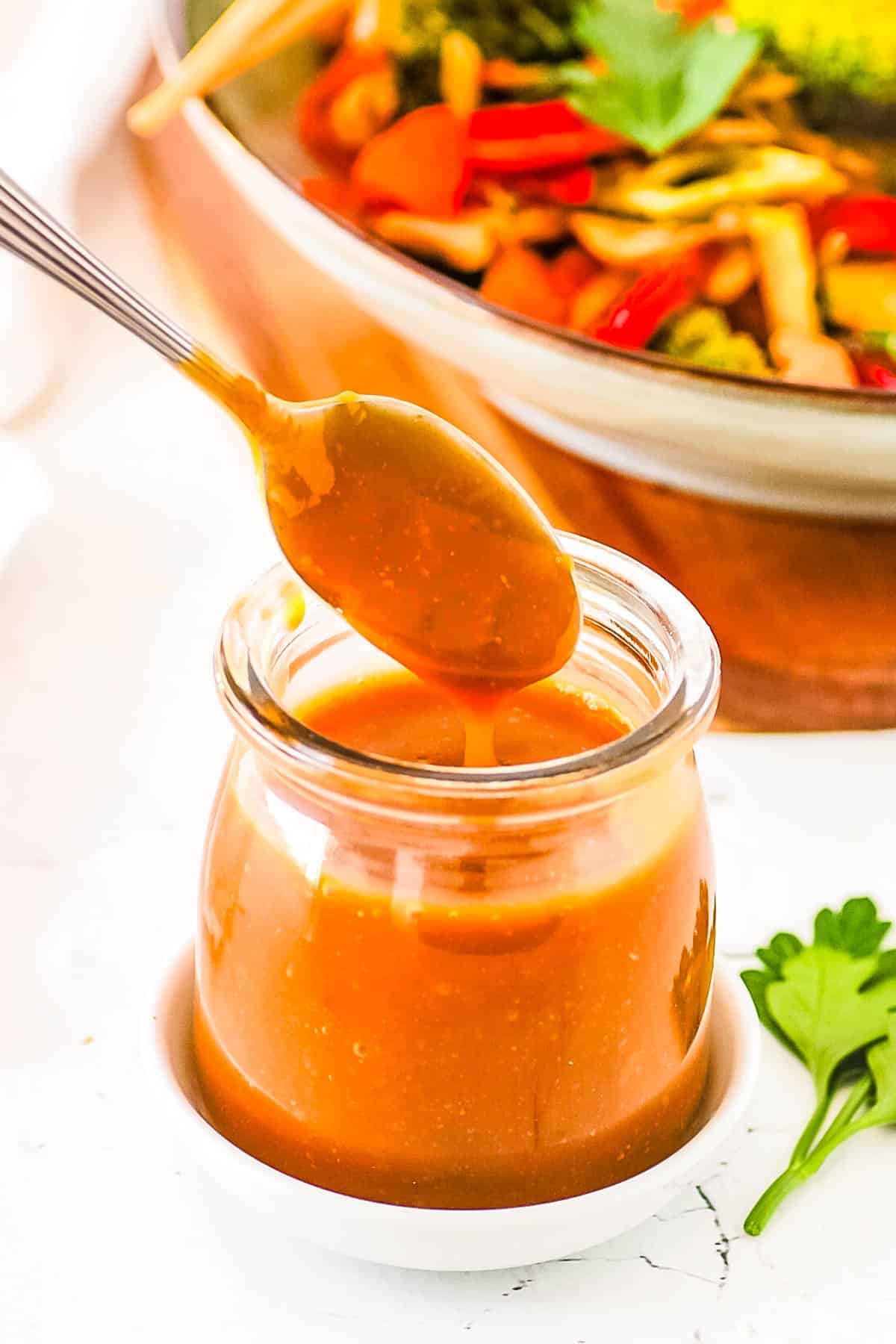 Healthy stir fry sauce, served in a gl، jar with a s،.