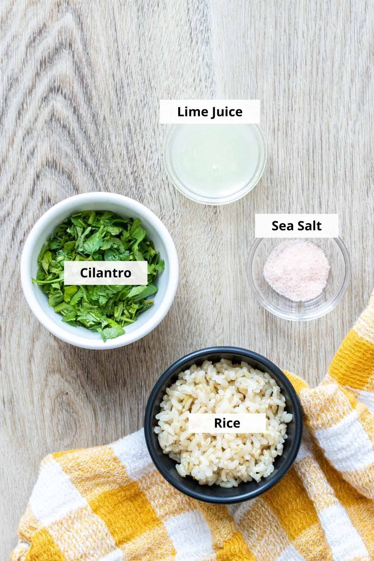 Bowls with cilantro, rice, lime juice and salt on a light wooden surface