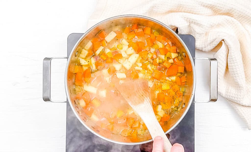 Veggies and broth simmering in a pot on the stove.