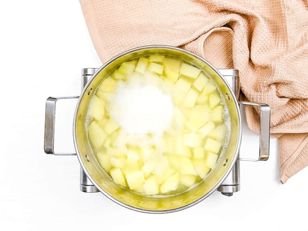 Potatoes boiling in water in a stock pot on the stove.