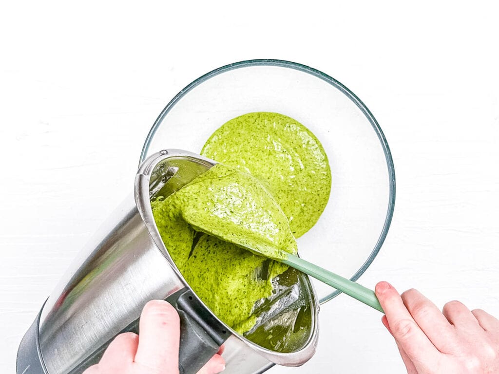 Green pancake batter being poured into a mixing bowl.