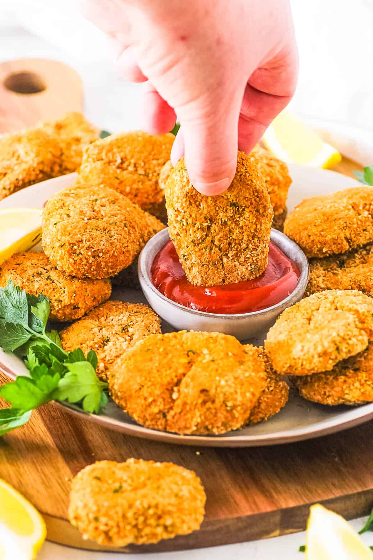 Vegan gluten free chicken nuggets being dipped into ketchup.