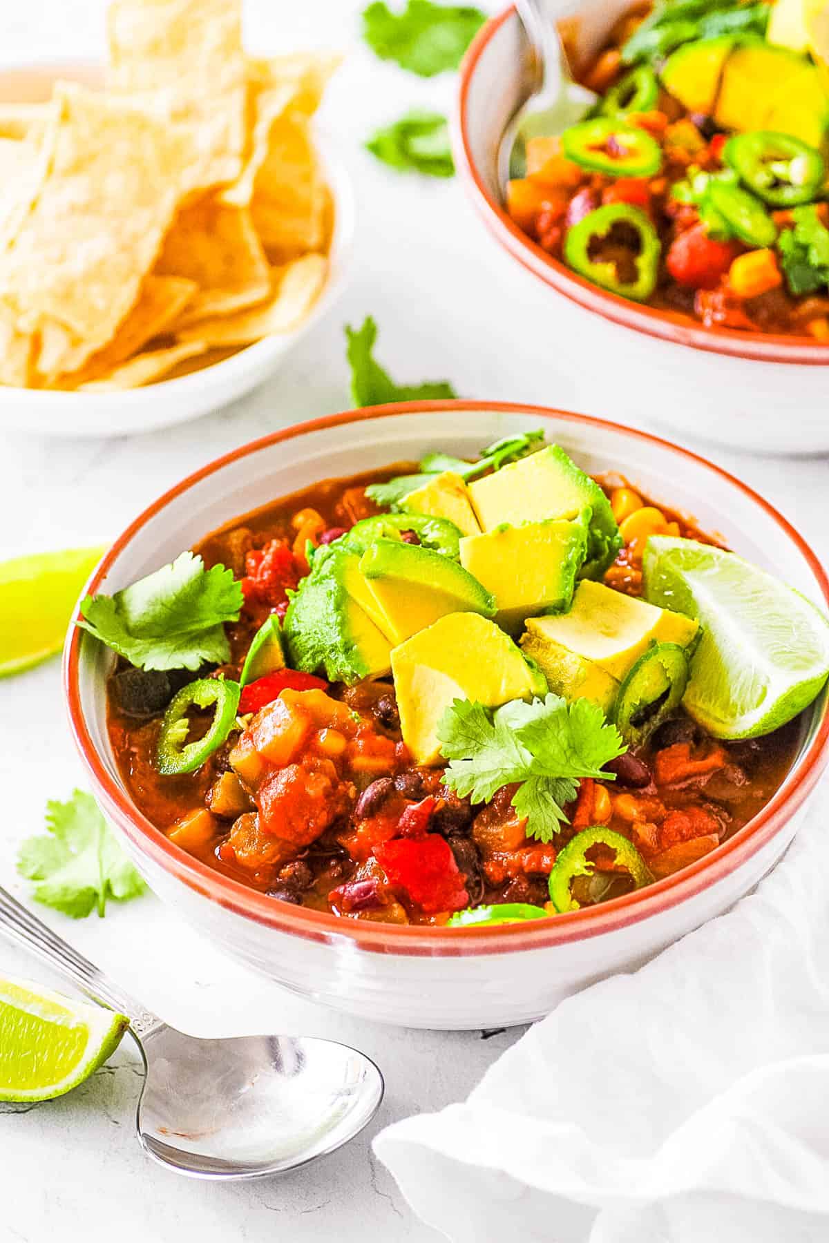 Vegan black bean chili, served in a white bowl, topped with avocado and lime.