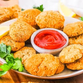 Vegan gluten free chicken nuggets served on a white plate with ketchup on the side.