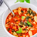 Easy vegan minestrone soup served in a white bowl with a spoon.