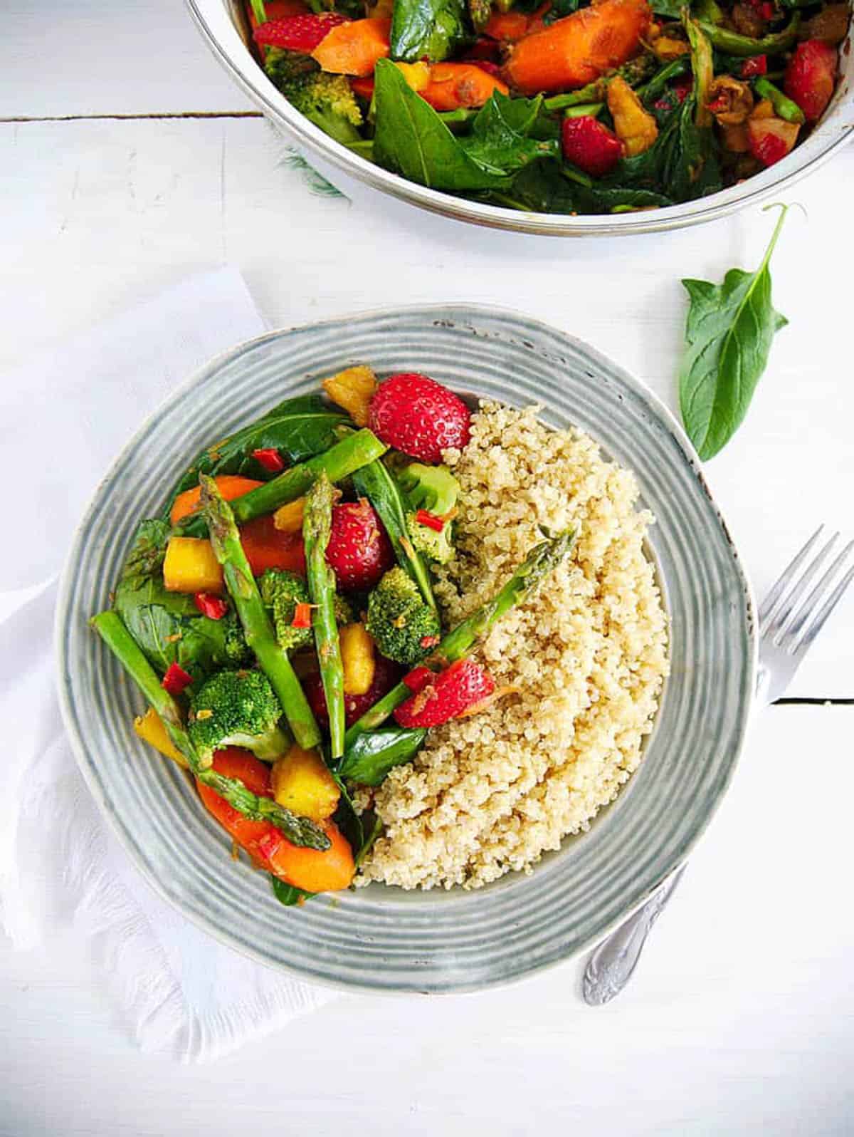 Vegetable stir fry served with brown rice on a grey plate.