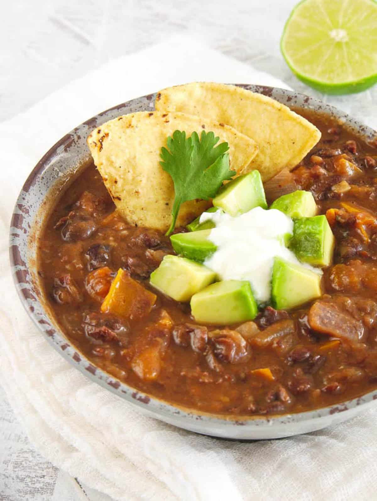 Closeup angled shot of a bowl of chunky black bean soup with avocado.