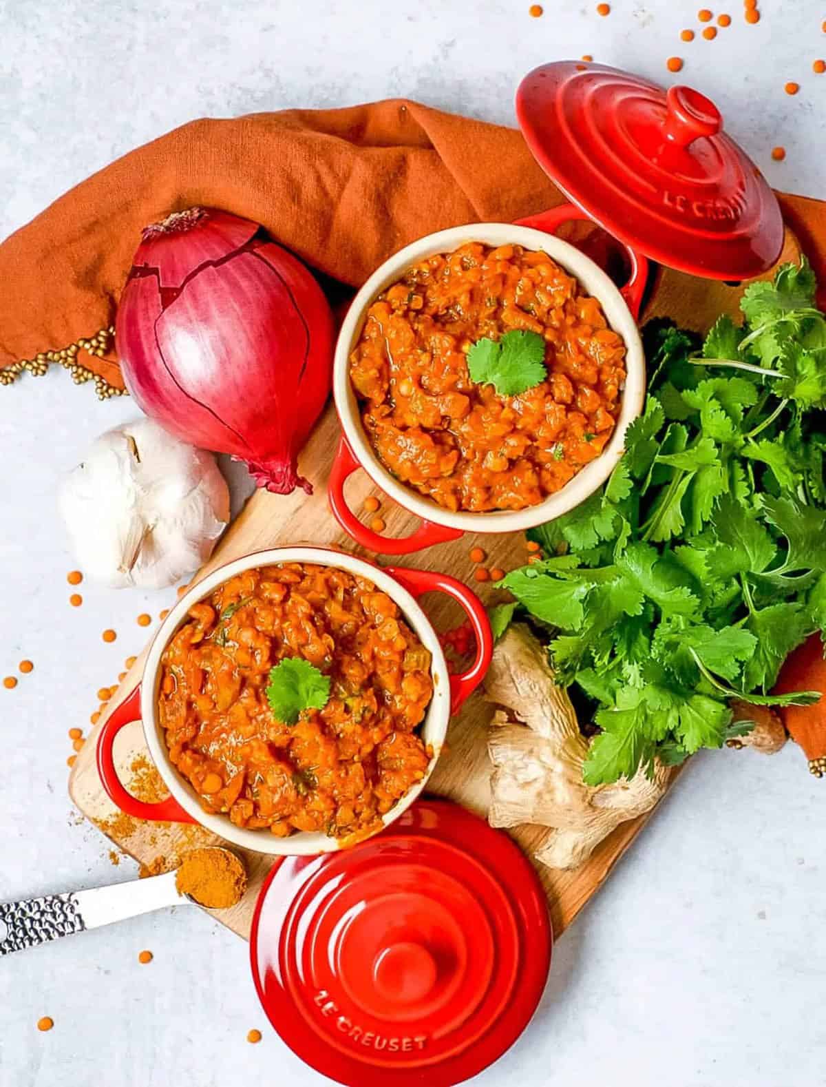 Red lentil dahl served in small ramekins with cilantro as a garnish.