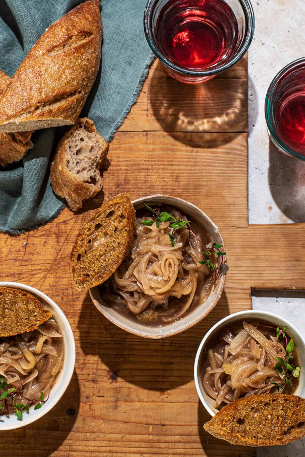 An overhead shot of small bowls of vegan french onion soup with toast.