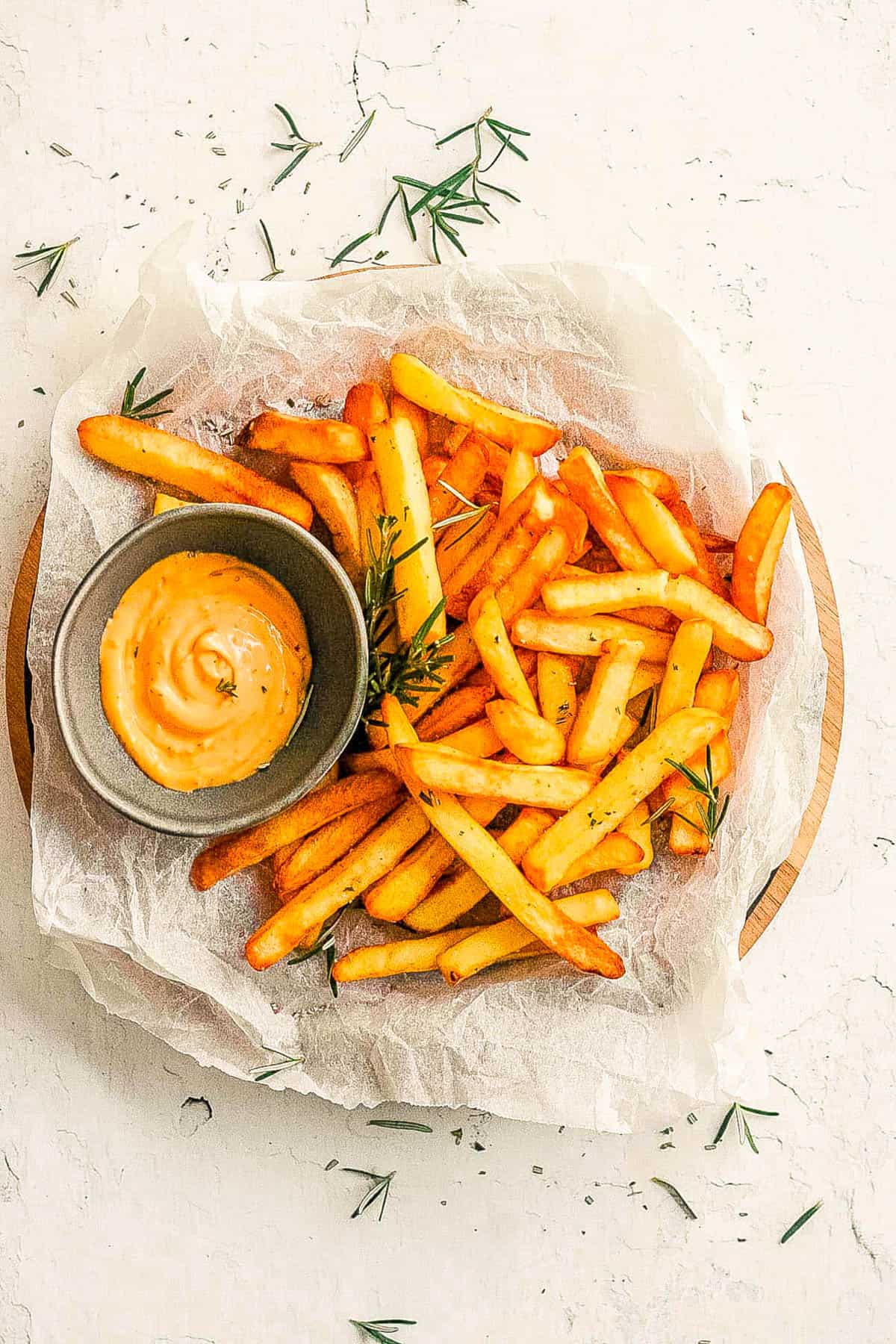 Air fryer frozen french fries on a white plate with dipping sauce on the side.