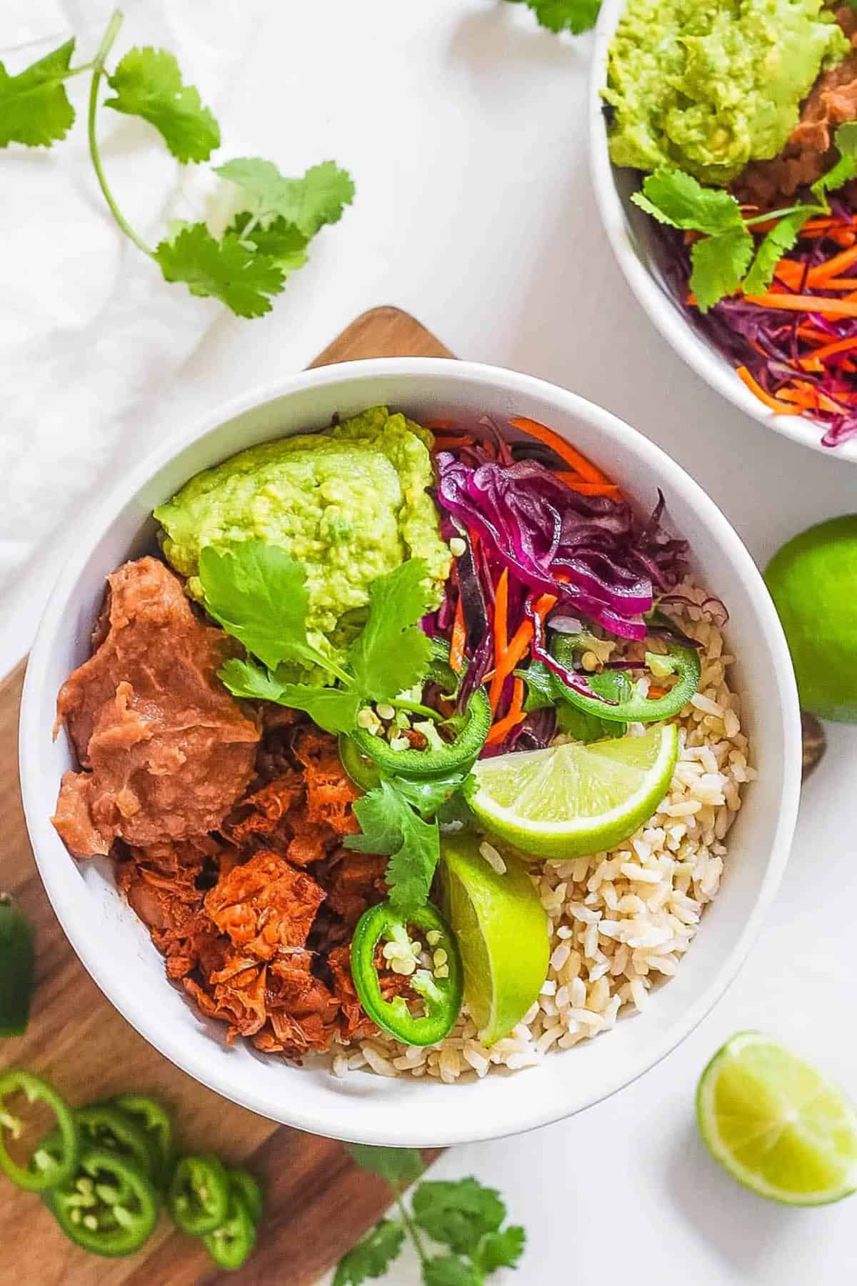 BBQ jackfruit burrito bowl served in a white bowl with rice on the side.