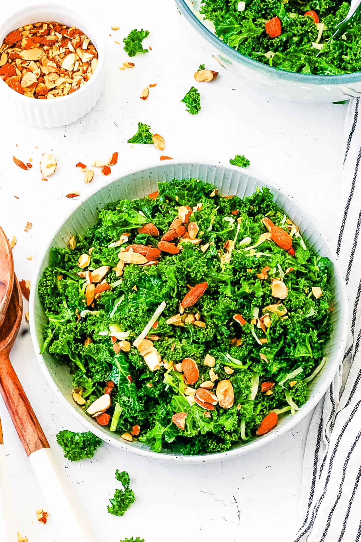 Copycat Chick-Fil-A kale salad served in a white salad bowl, garnished with almonds, top view.