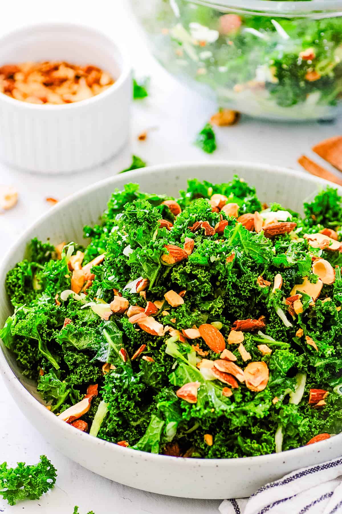 Copycat Chick-Fil-A kale salad served in a white salad bowl, garnished with almonds, side view.