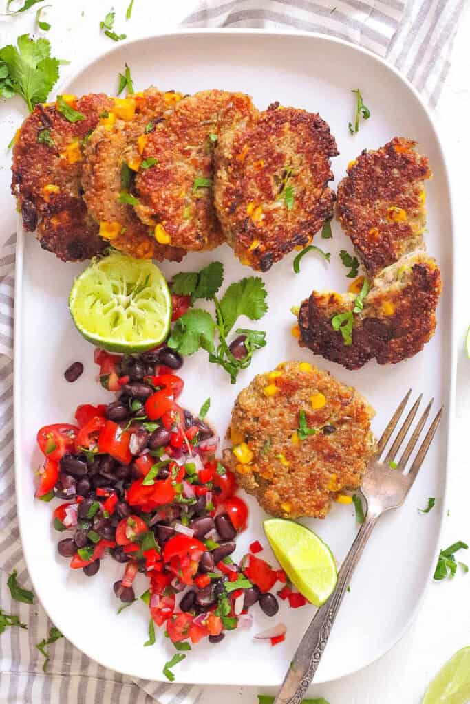 Sweet corn tamale cakes (Cheesecake Factory corn cakes copycat) served on a white plate with black bean salsa on the side.
