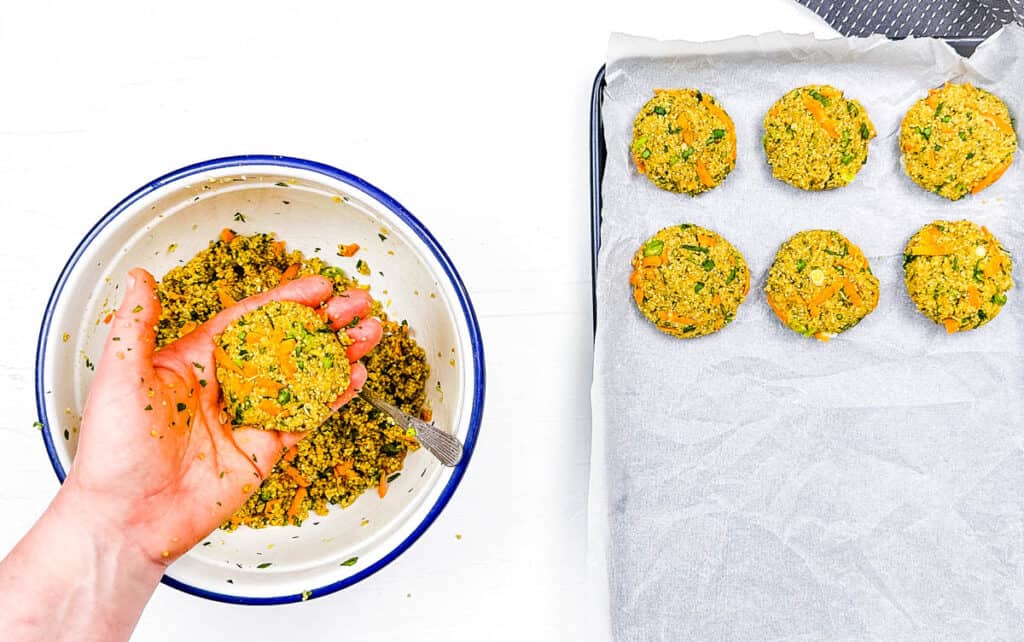 Vegan quinoa cakes being shaped by hands and placed on a baking sheet.