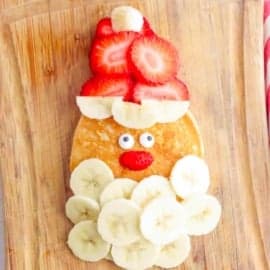 Overhead shot of a santa pancake on a wooden cutting board.