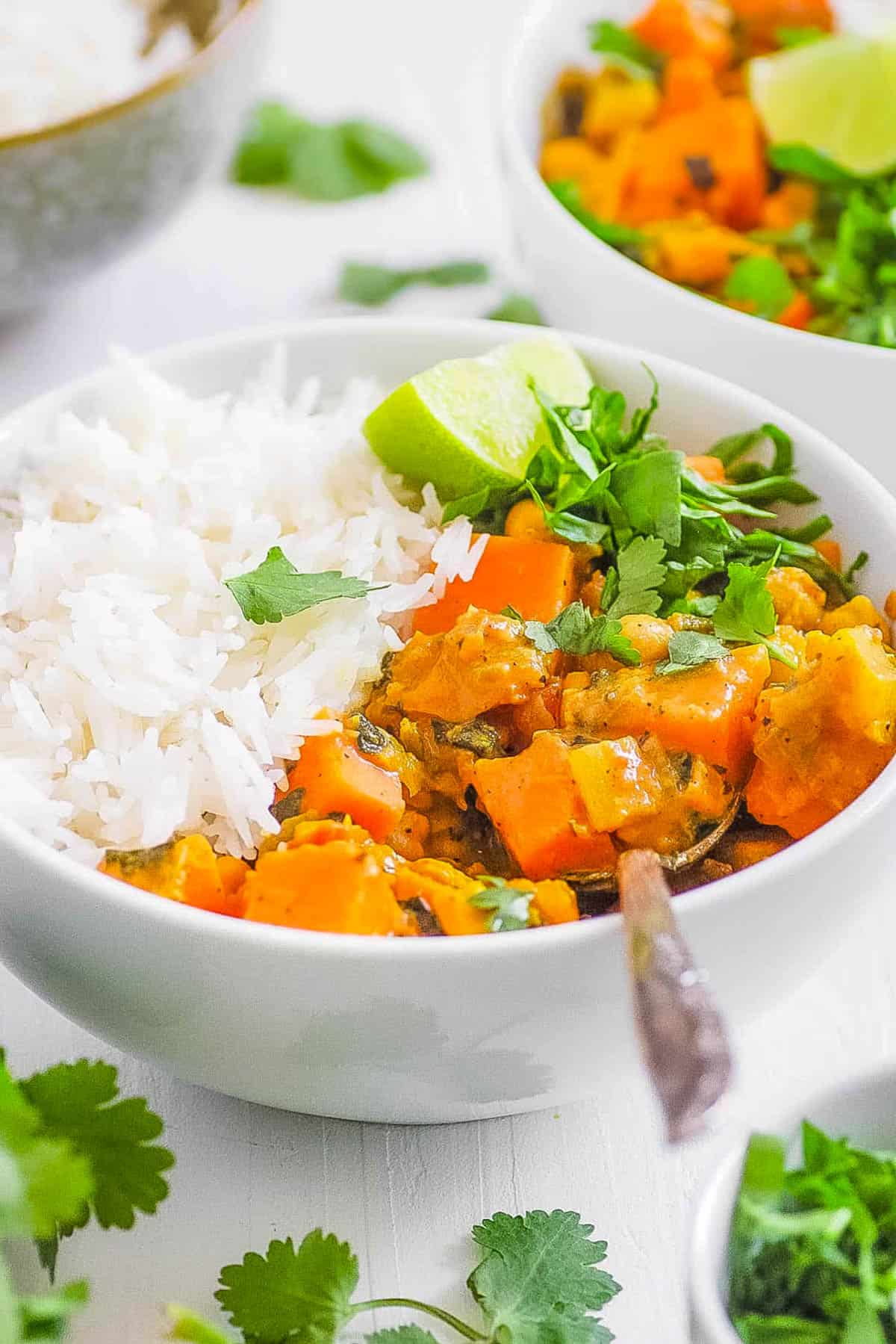Easy sweet potato and chickpea curry in a white bowl served with rice.