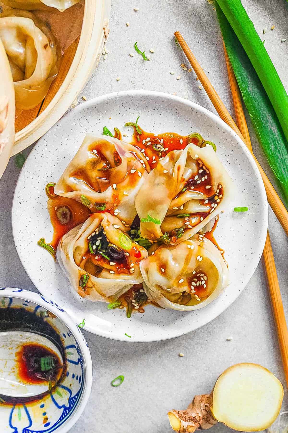 Vegan & vegetarian wontons made with mushrooms served on a white plate with dipping sauce.