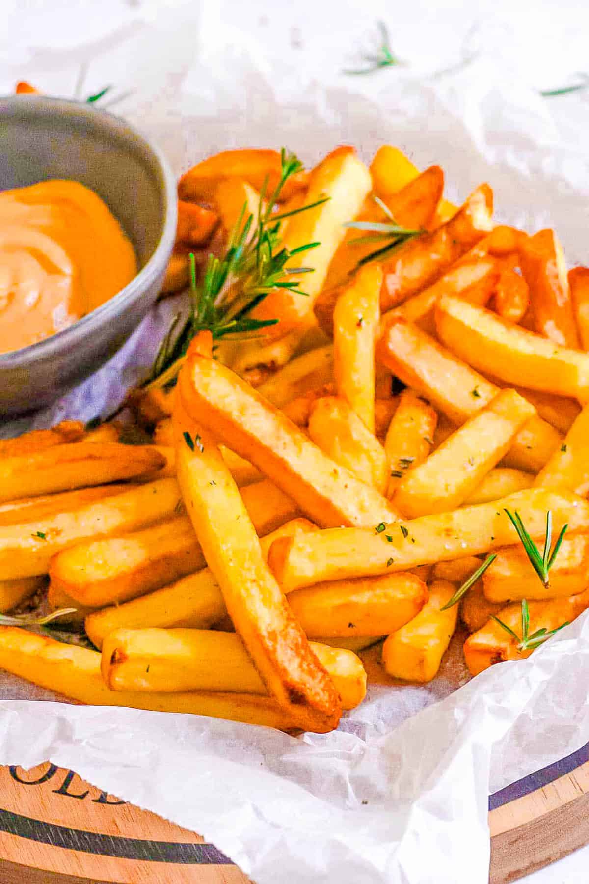 Air fryer frozen french fries on a white plate with dipping sauce on the side.