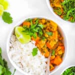 Sweet potato chickpea curry in a white bowl served with rice.